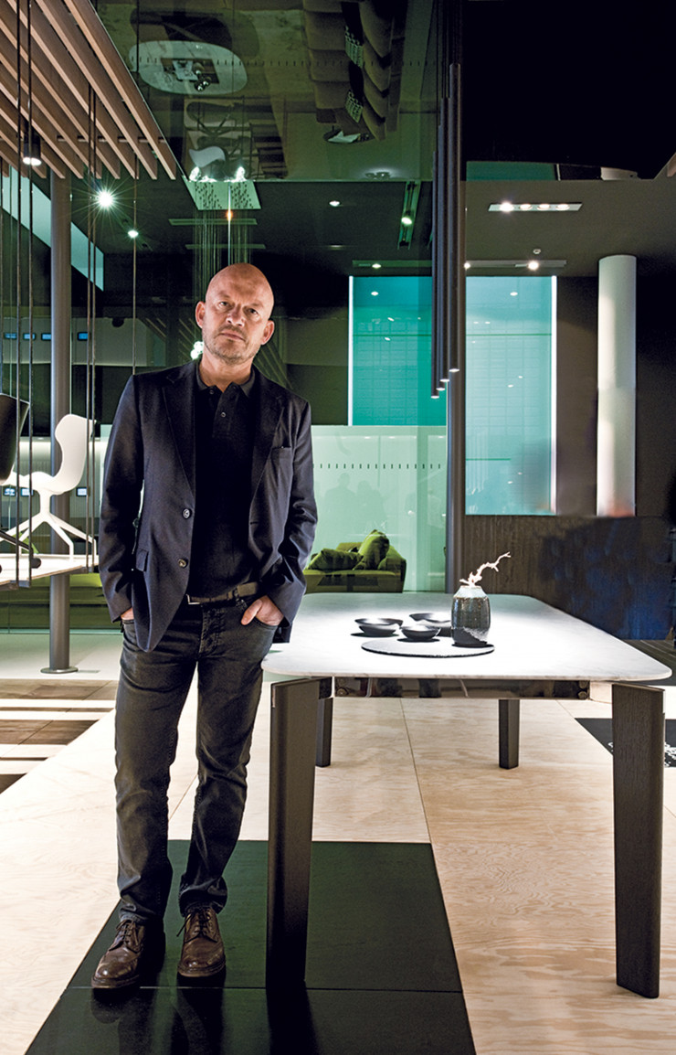 Vincent Van Duysen pose au Salon de Milan en avril dernier, au côté de sa table Oskar (B&B Italia).