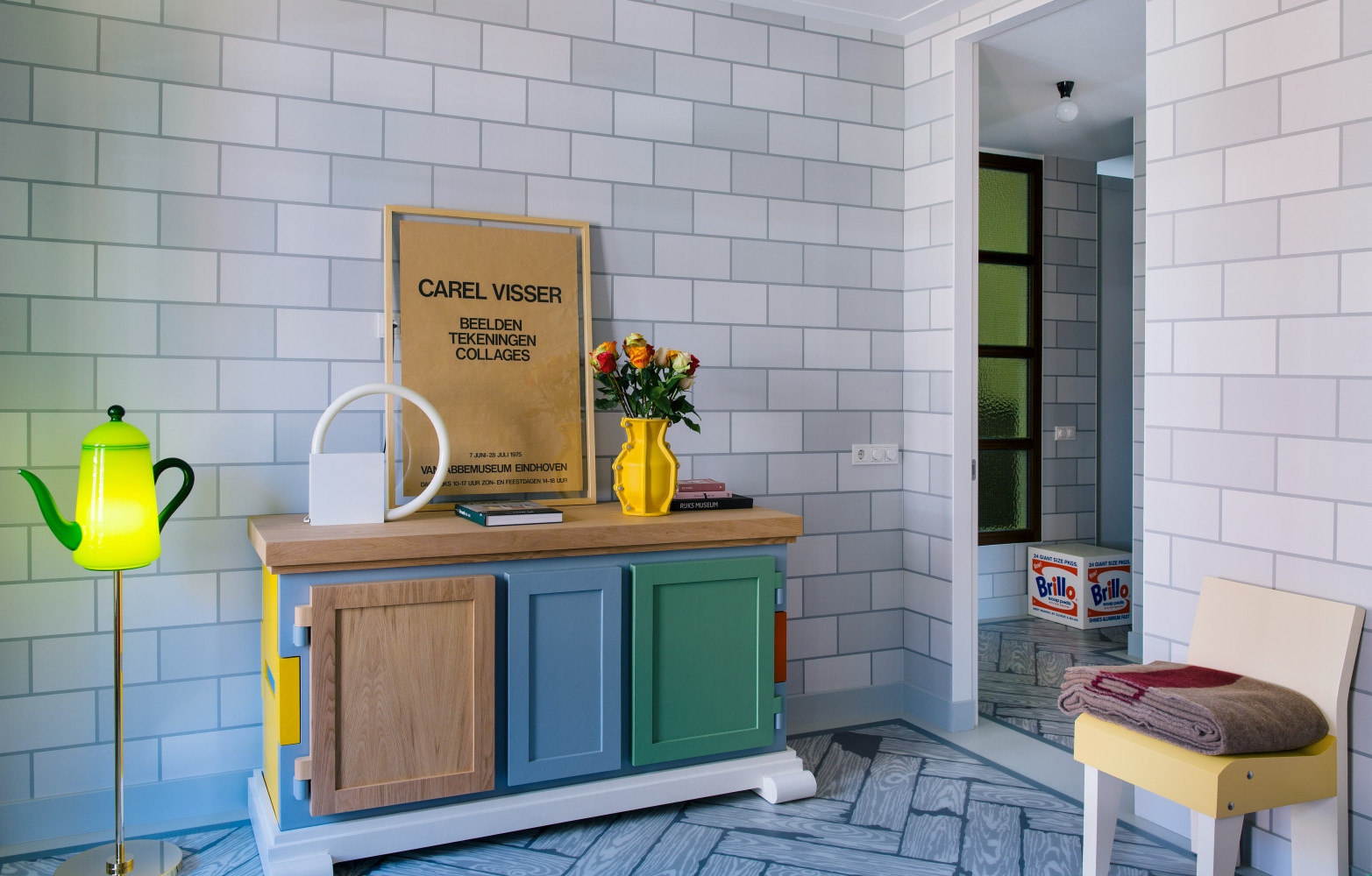Le papier peint Grey Brick met en valeur le Paper Buffet Patchwork (Moooi) et lampe sur pied...