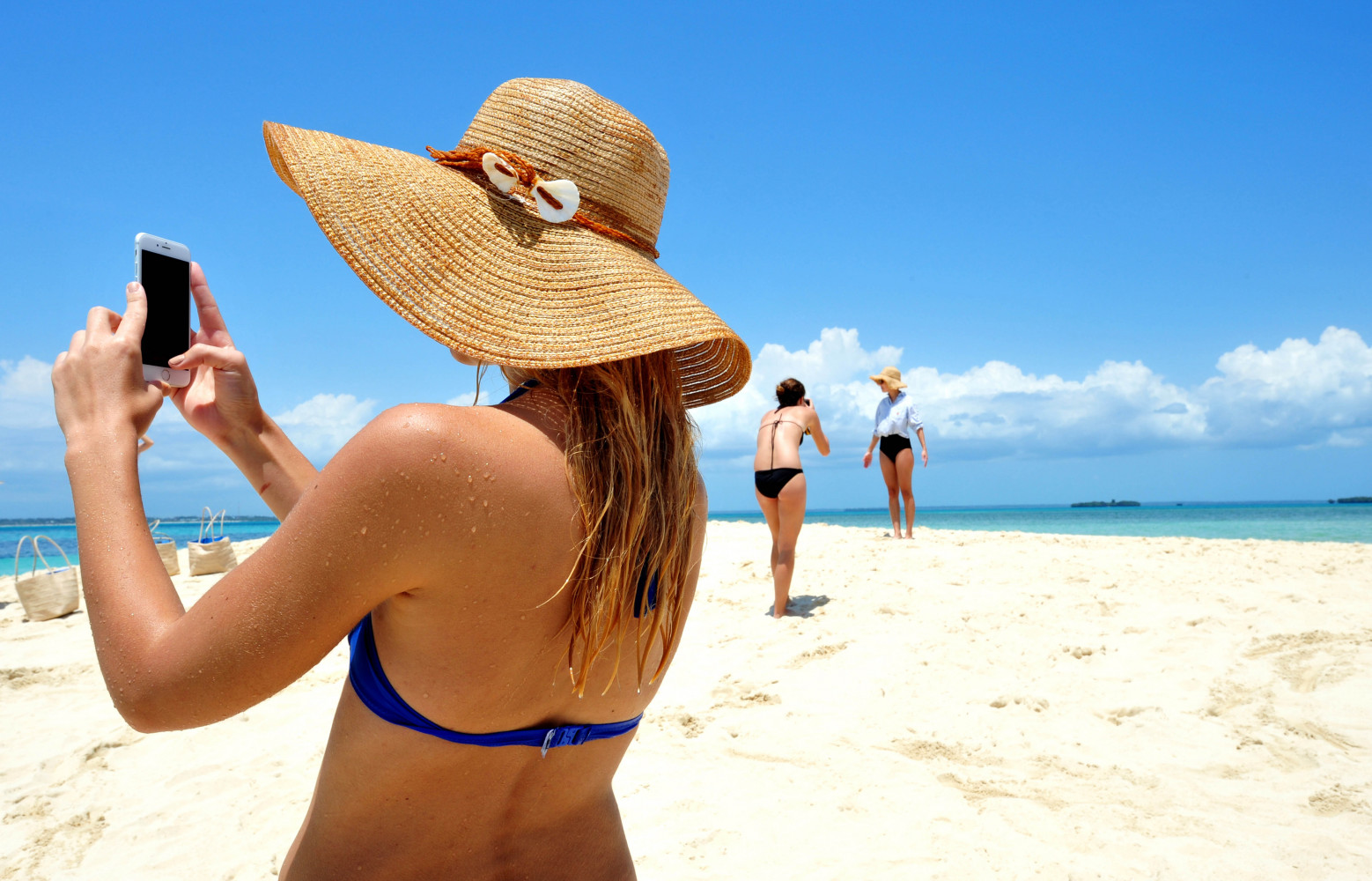 Femmes se prenant en photo sur un banc de sable au large de Zanzibar lors d'une croisière.