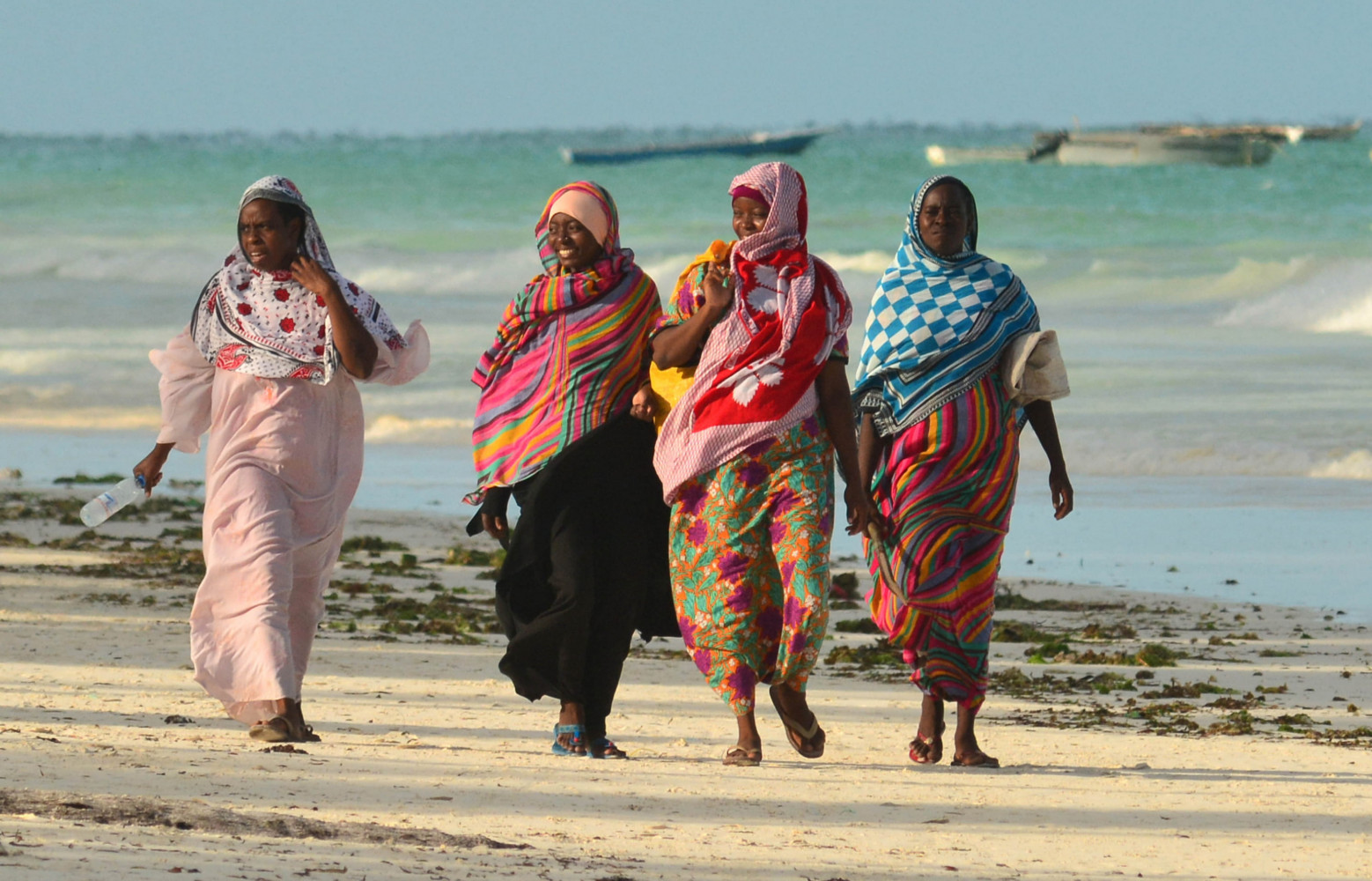 Femmes drapées dans leurs khangas sur une plage de la cote est de Zanzibar.