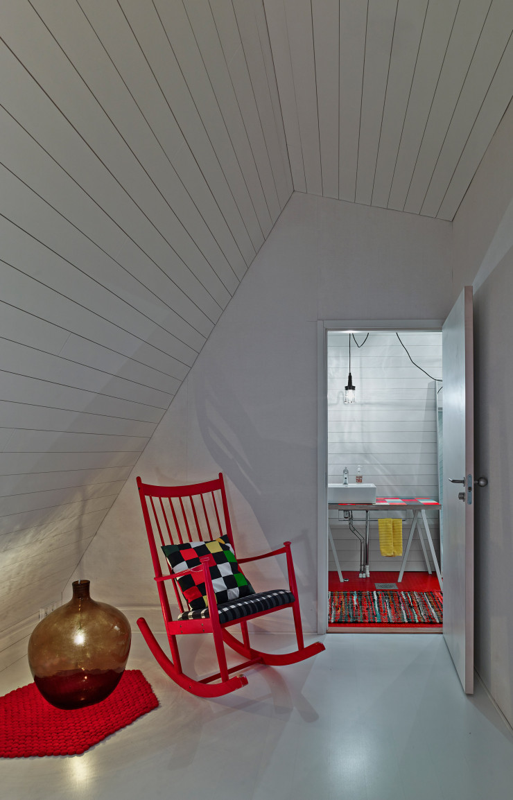 À l’étage, on retrouve les touches de rouge qui ponctuent toute la maison. Le rocking-chair et le grand vase posé sur le sol de ce petit salon appartenaient au grand-père du maître des lieux.