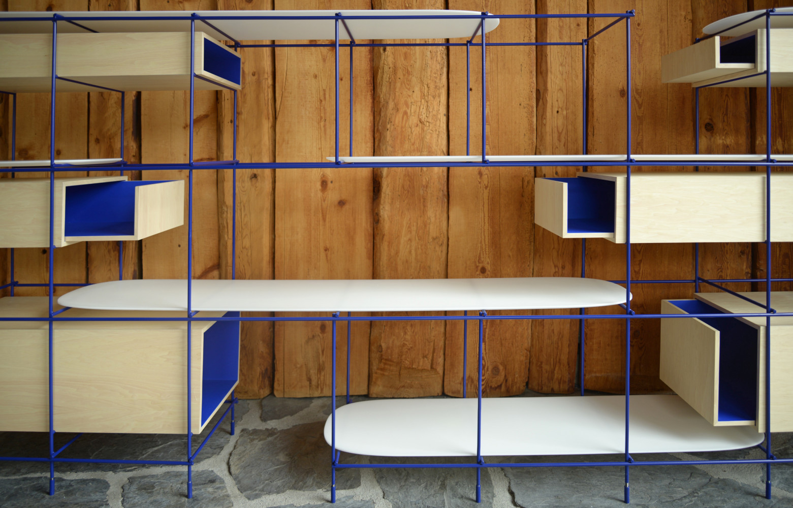 Bois blanchi et bleu Klein se marient au mur recouvert de pin verni.