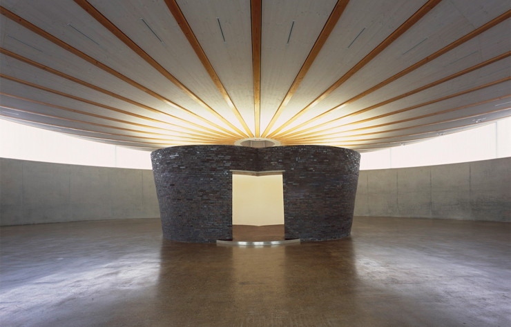 Forme ovoïde de l’espace, plafond convexe, lumière naturelle qui jaillit des ouvertures placées en hauteur, et une salle dans la salle, qui crée soudain un lieu d’intimité dans l’immense halle de 700 m2 que l’on embrasse d’un seul regard. Une sculpture architecturée pensée pour accueillir d’autres sculptures.