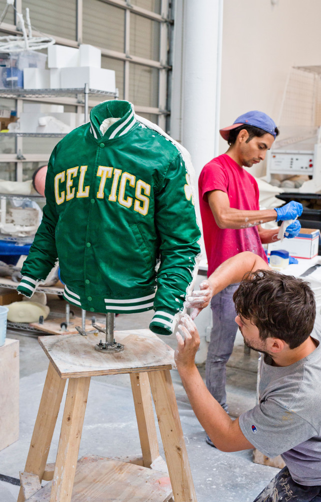 Deux assistants réalisent le moulage d’un bomber estampillé Celtics, l’équipe de basket de Boston.