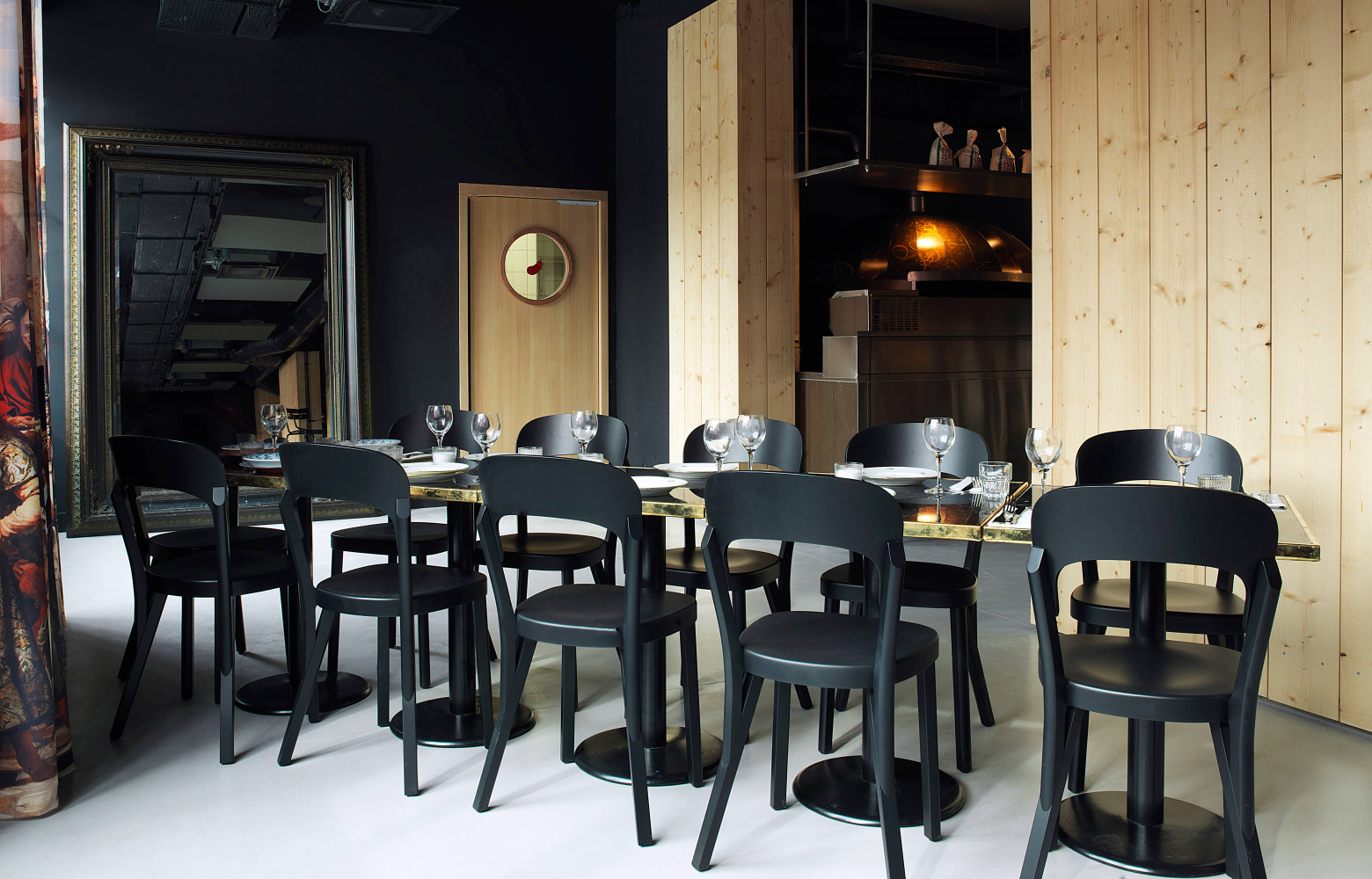 Dans la salle de la pizzeria, le bois des chaises répond à celui des murs, laissé brut....