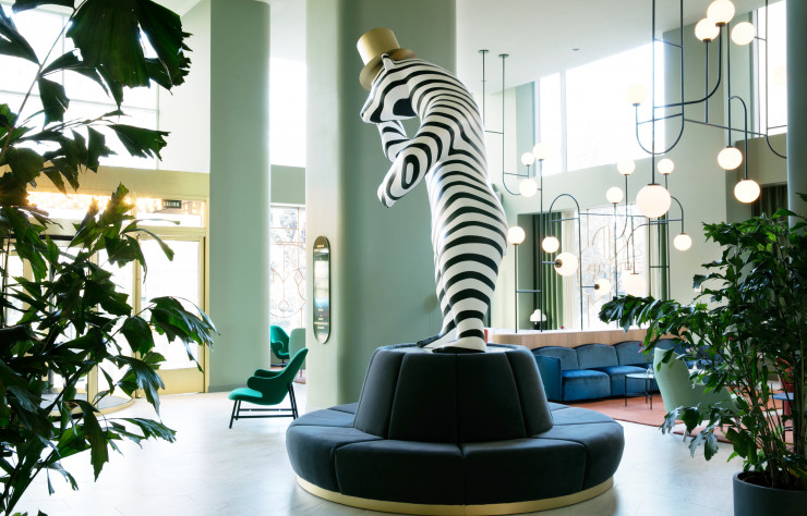 Une créature mi-ours mi-zèbre salue les clients de l’hôtel de son haut-de-forme… en or !