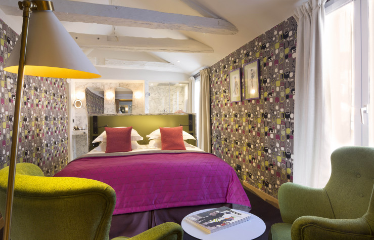 La chambre de la suite au dernier étage avec son papier peint graphique et ses couleurs quasi criardes.
