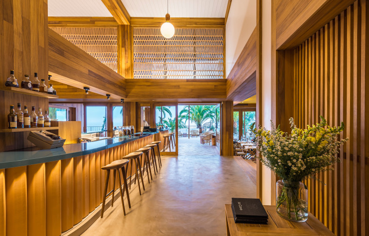Le bar, élégamment paré de bois dans un vocabulaire résolument contemporain, s’ouvre largement sur l’extérieur.