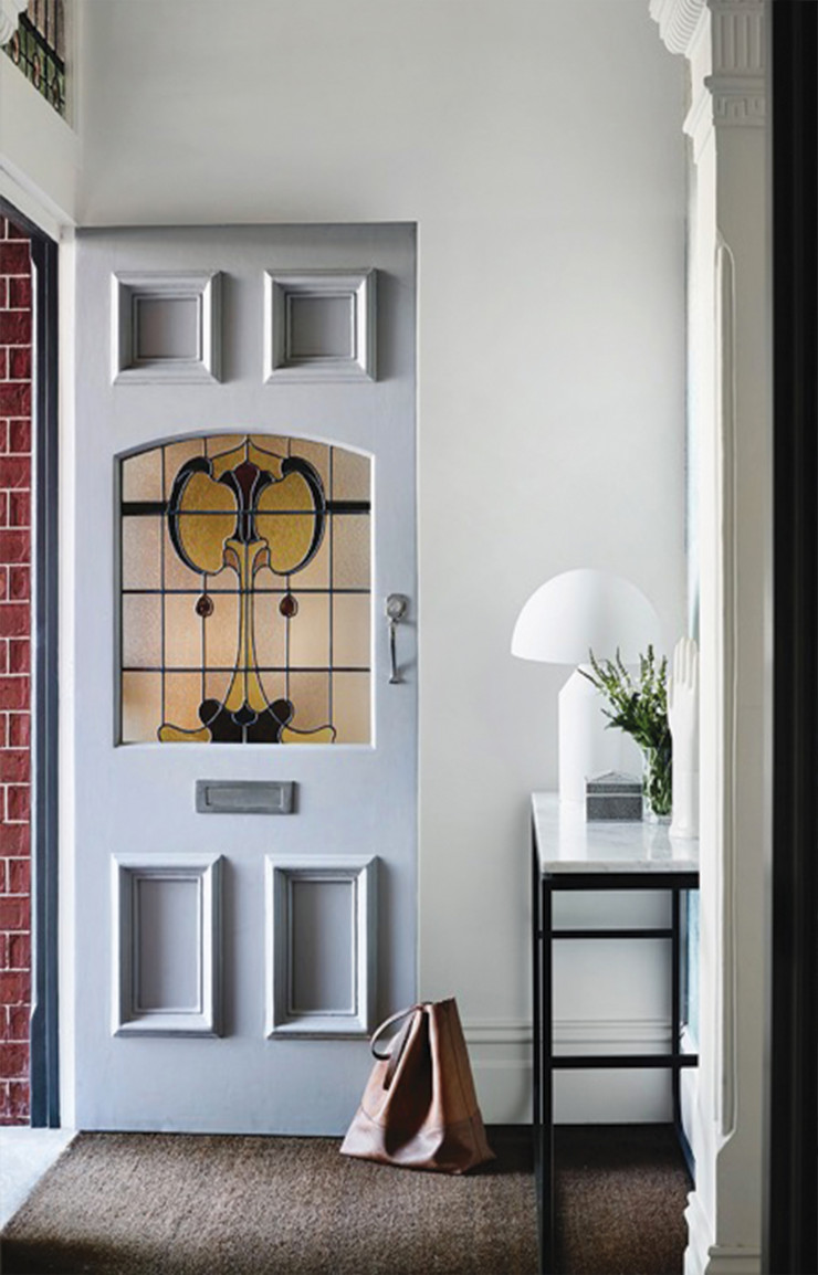 La porte tendance art déco s’ouvre sur une entrée lumineuse. Sur la console : lampe Atollo (Flos).