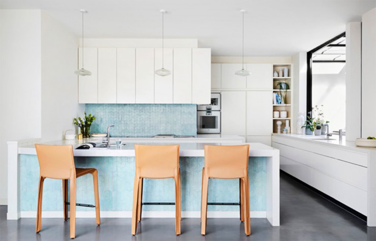 La cuisine ouverte blanche est décorée par un carrelage bleu en chevrons. Lauren Li a choisi les tabourets Cab Stools (Cassina).