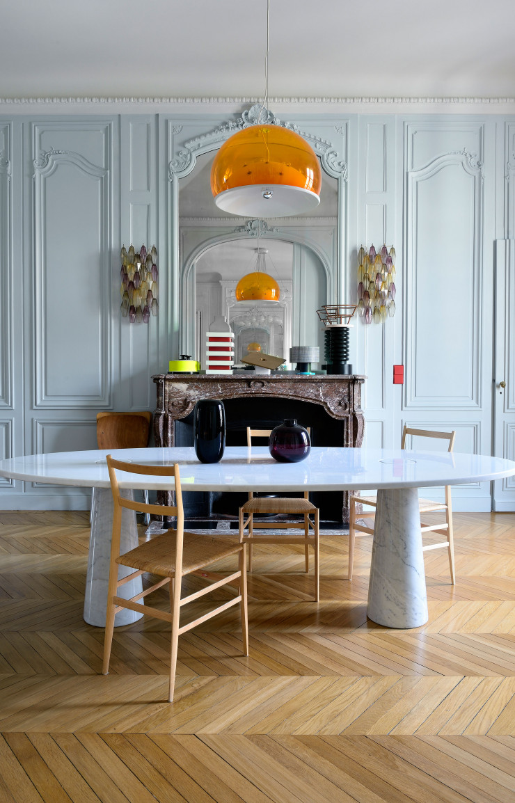 Dans la salle à manger dont le parquet en point de Hongrie a été conservé, la maîtresse de maison a joué avec les couleurs acidulées en transparence. Les chaises Superleggera de Gio Ponti (Cassina) sont disposées autour de la table Eros d’Angelo Mangiarotti (Agapecasa, 1971). Au-dessus, suspension n° 604, dite « Moon » (1969), de Gino Sarfatti. Deux appliques en verre attribuées à Carlo Scarpa (Venini) encadrent le miroir. Sur la cheminée, céramiques chinées d’Ettore Sottsass, d’Andrea Branzi, de Georges Jouve et de Bruno Gambone.