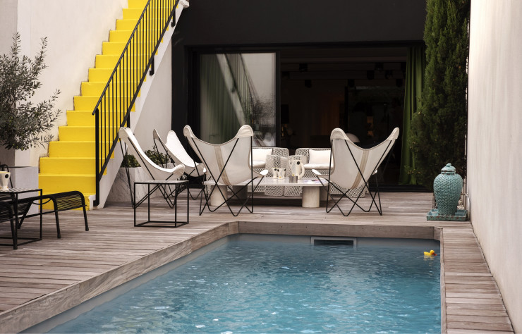 Tandis que les fauteuils « Butterfly » prennent place en vis à vis de la façade, le jaune, meilleur allié du noir, contraste avec les lignes strictes du garde-corps.