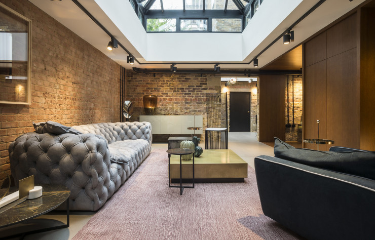 A l’arrière, les briques s’associent au chêne teinté de la bibliothèque pour créer des espaces plus intimes et inviter à la détente, à l’image du sofa « Chester Moon » de Paola Navone (Baxter).
