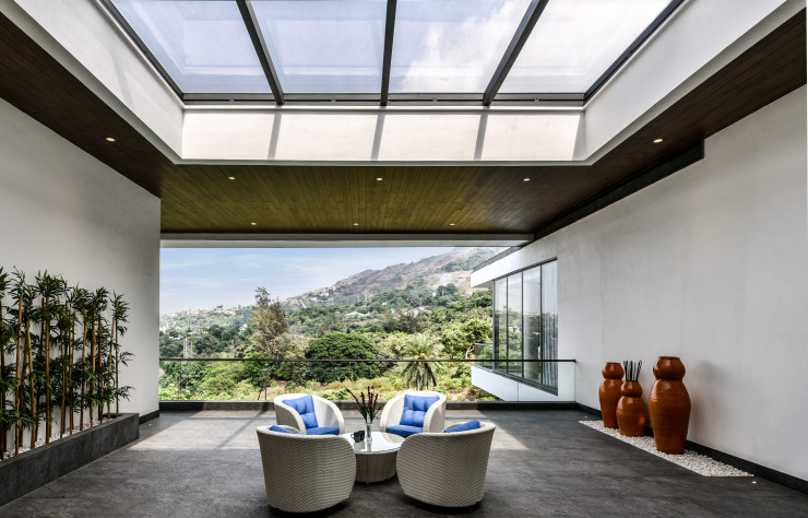 Abritée par les décrochés de la toiture et une verrière, une terrasse s’installe entre les chambres qui cadrent le paysage.