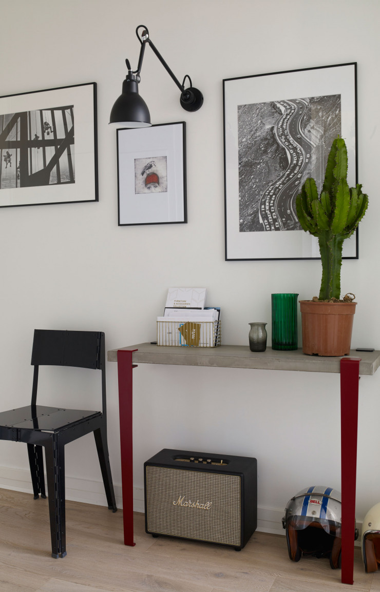 Dans l’entrée, la console : un plateau en béton et deux pieds en acier (Tiptoe). Applique 204 L 40 (Lampe Gras par DCW Éditions). Photos de Ruby Bou Chebel. Au centre, deux illustrations de Shabnam Zeraati. Carafe (Doiy au Bon Marché). Chaise Stitch d’Adam Goodrum (Cappellini). Cactus (Truffaut).