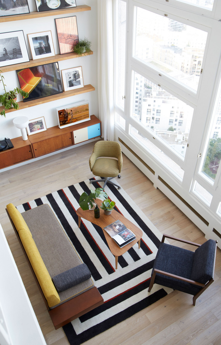 Depuis la mezzanine, vue plongeante sur le salon. Sur les meubles de rangement suspendus Bala (Kann Design), le téléviseur Sérif de Ronan et Erwan Bouroullec (Samsung) diffuse un film de Wes Anderson cher à Houssam et Meghedi : À bord du Darjeeling Limited. Tapis Four Corners de Jason Miller (La Manufacture Cogolin). Banquette tapissée Bi Back, dessinée par Meghedi Simonian. Table basse Vy et fauteuil Kora à ossature bois du designer José Pascal (le tout, Kann Design).