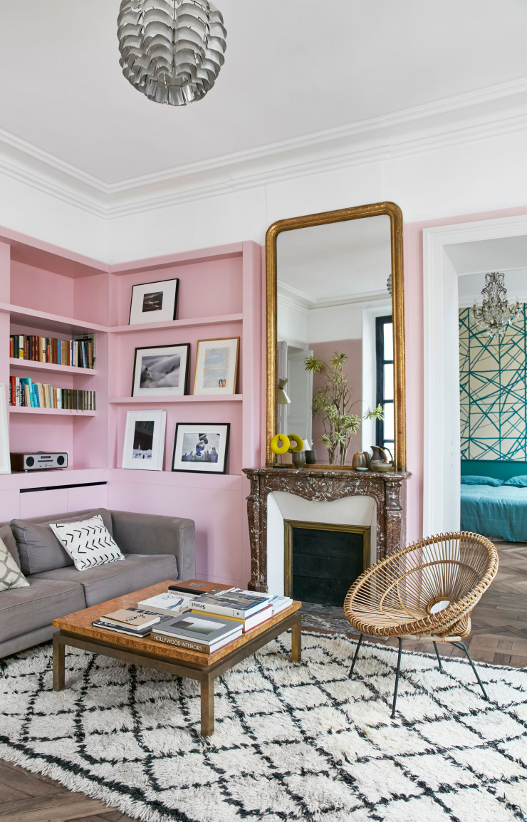 Entre la cuisine et la chambre d’amis, le coin salon est aussi chic que cosy malgré la hauteur sous plafond. Fauteuil en rotin attribué à Franco Albini et Janine Abraham. Table basse en bois des sixties. Canapé Caravane. Tapis berbère Beni Ouarain rapporté du Maroc. Dans la bibliothèque rose, les photos encadrées sont (de haut en bas et de gauche à droite) de Roman Loranc, de Marc Riboud à côté d’une lithographie de Michel Debré, de Saul Leiter et une autre de Marc Riboud.