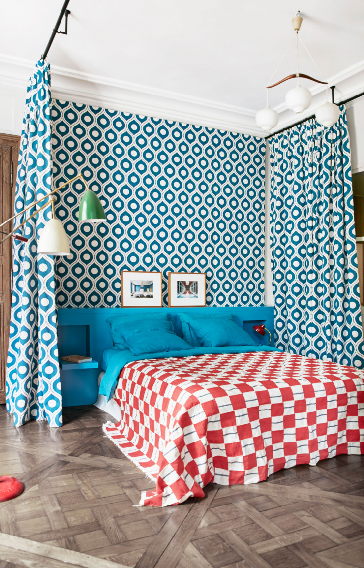 Dans la chambre parentale, rideaux bleu paon de Florence Broadhurst et couvre-lit en tissu kenté vintage du Ghana (trouvé chez Amatuli à Johannesburg). Lustre de Børge Mogensen et lampe sur pied italienne des sixties chinée aux puces à Paris. Au-dessus du lit, deux photos de Candida Höfer.