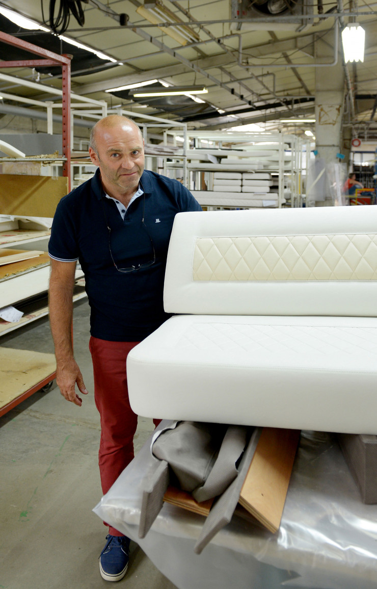 Olivier Poupart, le responsable de l’atelier couture et tapisserie, pose avec une banquette de bateau réalisée par Atelier Burov.