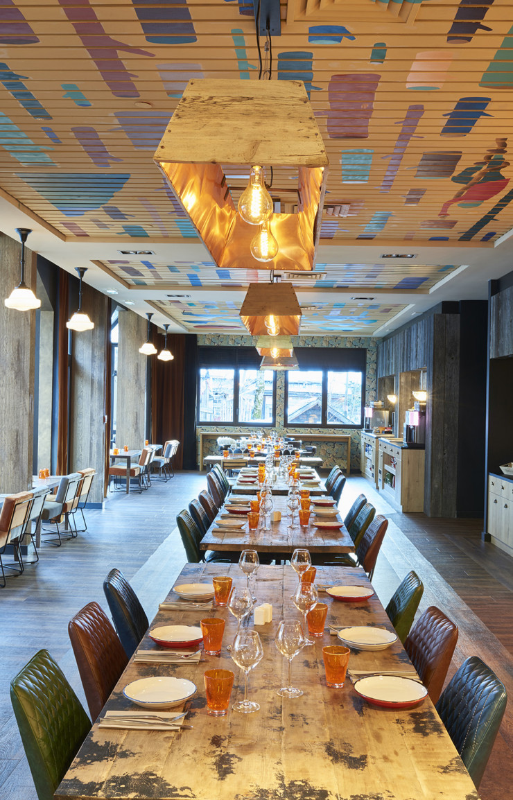 Dans le restaurant, les couleurs des chaises et de la vaisselle dialoguent avec une autre intervention de v2m, au plafond cette fois.