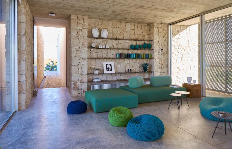 Meublé en Paola Lenti comme la terrasse, le séjour se pare de vert et de bleu. Sur les étagères : sculptures blanches provenant de Monreale, près de Palerme ; collection de vases Made a Mano ; en bas, à gauche, lampe Shen en verre et ciment, design Marco Merendi (Kundalini). À droite, luminaire Parentesi, design Achille Castiglioni et Pio Manzù (1971, Flos).