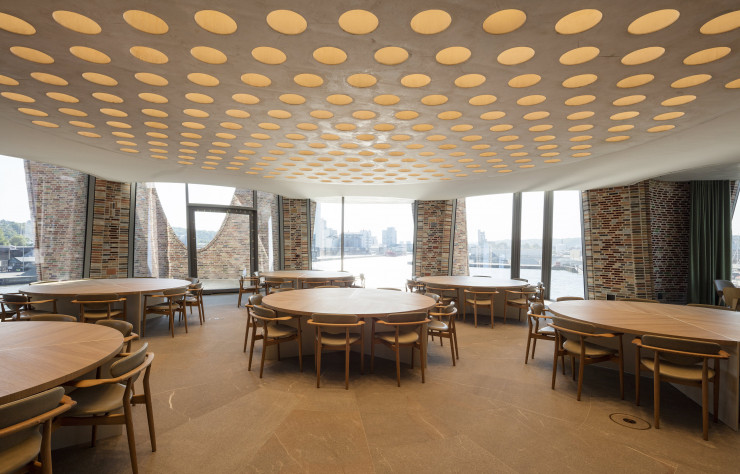 Au-dessus du mobilier sur-mesure dessiné par le studio Olafur Eliasson, les percements circulaires accueillent l’éclairage tout en allégeant la dalle de béton.