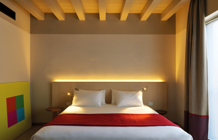 Dans les chambres, les poutres apparentes témoignent du bâtiment originel. Lumière et couleurs ont été dosées à la perfection par Aldo Cibic