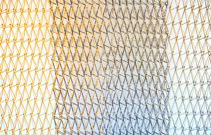 Détail d’un tissage complexe en trois dimensions de tubes de métal en finition or rose, nickel et ruthénium.