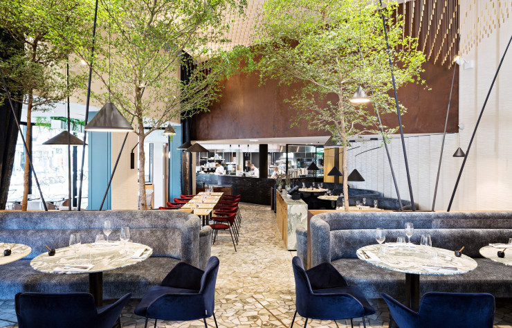 Les chaises Gubi, en velours bordeaux ou bleu nuit, accompagnent les banquettes sur-mesure.