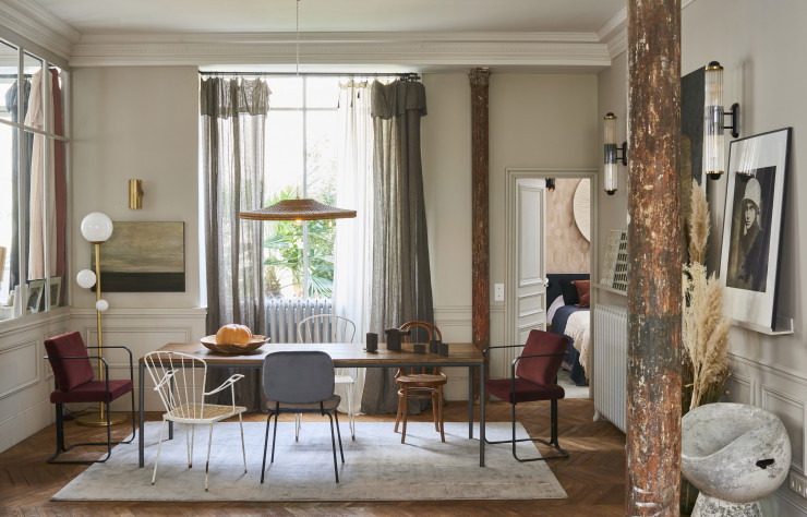 La salle à manger concentre une série de tableaux de Jeni Camdessus. Grande photo en noir et blanc de Paolo Roversi. Autour de la table, sur un tapis « Éclat », en laine (Toulemonde Bochart), s’alignent des chaises fifties de designers danois et une chaise en bois courbé Thonet. Le lampadaire « La Prudente » est signé Desjeux Delaye (Melissa Regan Editions)