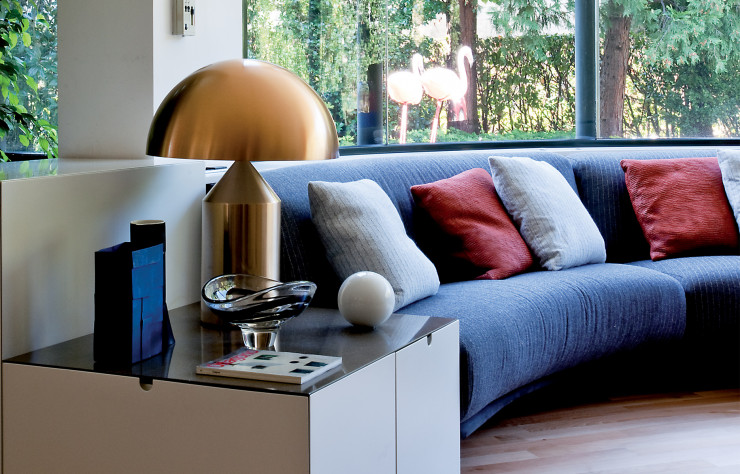 Au rez-de-chaussée, le sofa sur mesure du salon épouse l’architecture. Dans cet îlot de confort, les objets sélectionnés contribuent à la personnalisation de l’espace, qu’il s’agisse d’une lampe Atollo dorée de Vico Magistretti (Oluce), d’un vase en fer d’Antonino Sciortino ou d’une coupe en verre de Carlo Moretti.