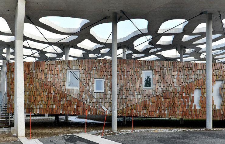 Le module d’habitation conçu par Kengo Kuma se couvre de tavillons, petites pièces de bois assemblées (par l’artisan romand Olivier Veuve) pour un effet isolant et décoratif, évocateur d’une région agricole arborée mais surtout de l’archétype de la cabane…