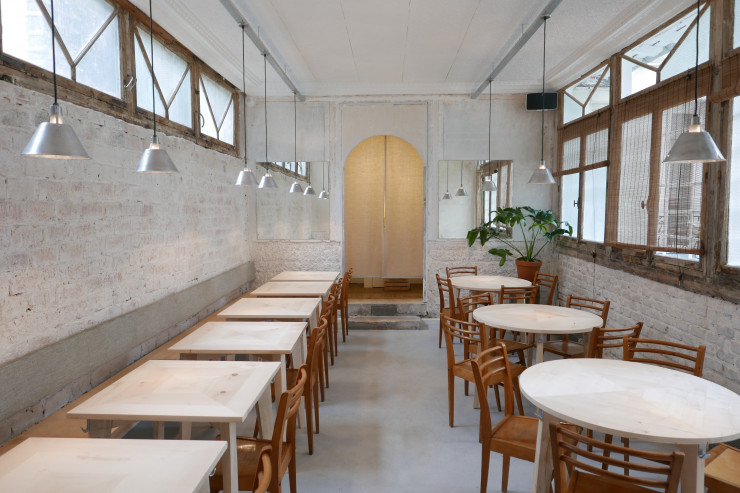 Lumineux et épuré, le décor fait de murs blancs, parquets, tables hautes et discrets luminaires a été conçu par le studio Ciguë.