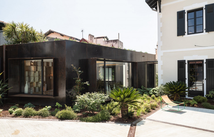 Pour Entre:temps, le showroom de Delphine Carrère à Biarritz, une extension en acier Corten modernise la maison d’origine dont la cour a été végétalisée. Eclairage Viabizzuno, chaise Valerie Objects, jardin paysagé Michel Mendiboure.