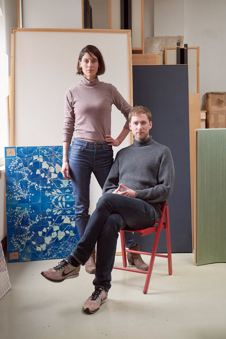Sarah Van Gameren et Tim Simpson, les deux designers de Glithero, dans leur studio londonien, devant un panneau de leurs carreaux « Botanical Tiles ».