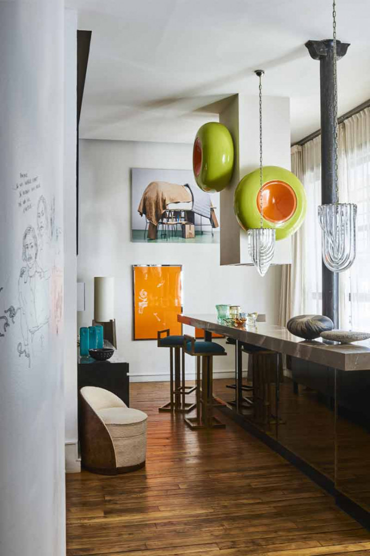 Au-dessus du bar, suspensions en verre de Murano datant des années 70. Sur la demi-colonne d’aération, deux éléments de décor de théâtre en céramique dégotés chez Emmanuel Renoult aux puces de Saint-Ouen. Tabourets de bar en laiton brossé (Maison Jaune Design, aux puces de Saint-Ouen). Au mur, affiche orange réalisée par M/M pour Les Inrocks. Au-dessus, photo Sans titre (Éléphant), 2008, de Geoffrey Cottenceau et Romain Rousset (galerie La Station, à Nice).