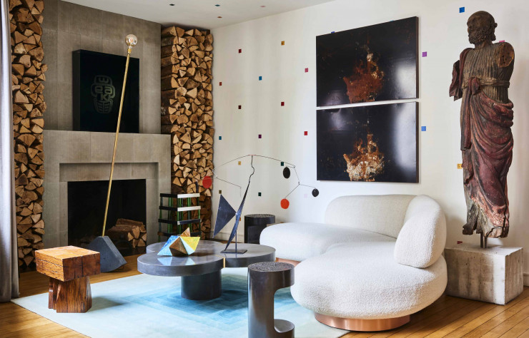Dans le salon, autour de la table basse Clover en béton avec joints en laiton, du Studio Profil Bas (Malherbe Edition), sofa Niko et tables d’appoint de Thierry Lemaire (The Invisible Collection). Sur la table, mobile cinétique vintage et céramique Origamien terre émaillée polychrome de Jacotte Capron (Drouot). Devant la cheminée, luminaire PI/2 avec socle en béton et structureen laiton, design Hugues Weill (Malherbe Edition chez Silvera). À droite, statue de saint Pierre du XIXe siècle. Au mur, photos Untitled (2018), de Loris Gréaud (sérigraphie sur plaque métallique oxydée, vernis mat). Tapis en laine noué à la main Codimat Collection.