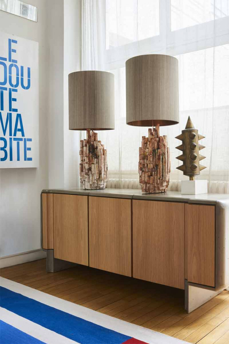 Sur le buffet en chêne habillé d’un revêtement en béton fibré (Malherbe Edition), deux lampes en céramique de Thierry Lemaire. À droite, sculpture réalisée à partir d’une arme du Moyen Âge montée sur un socle.