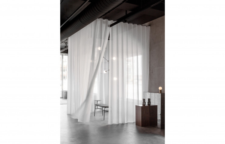 Dans ce même espace, un système de rideaux fait office de séparateur afin d’offrir des zones plus intimes pour le travail ou les réunions.