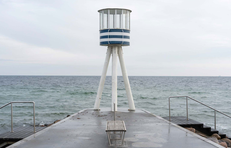 D’un blanc immaculé, le poste de surveillance revêt trois bandes bleu azur qui le rendent identifiable en un clin d’œil. Signature de Bellevue Strand, il incarne ainsi parfaitement le travail de Jacobsen à Gentofte.