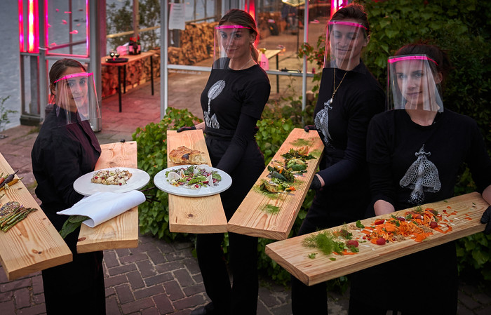 Les serveurs du Mediamatic Eten sont équipés de protections et proposent les plats à leurs clients grâce à des planches de bois.