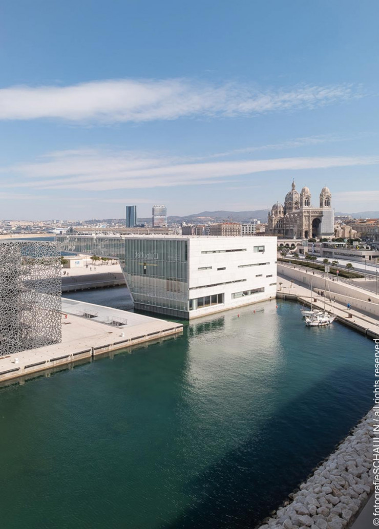 Enchâssé dans sa résille de béton, le musée des Civilisations de l’Europe et de la Méditerranée (Mucem) semble flotter sur le port. Œuvre de l’architecte Rudy Ricciotti, l’extraordinaire construction est modelée dans un béton fibré à ultra-haute performance. Elle offre l’une des promenades urbaines et maritimes les plus époustouflantes qui soient, entre rampes enroulées autour du bâtiment, terrasses et passerelles tendues du fort Saint-Jean au quartier du Panier.