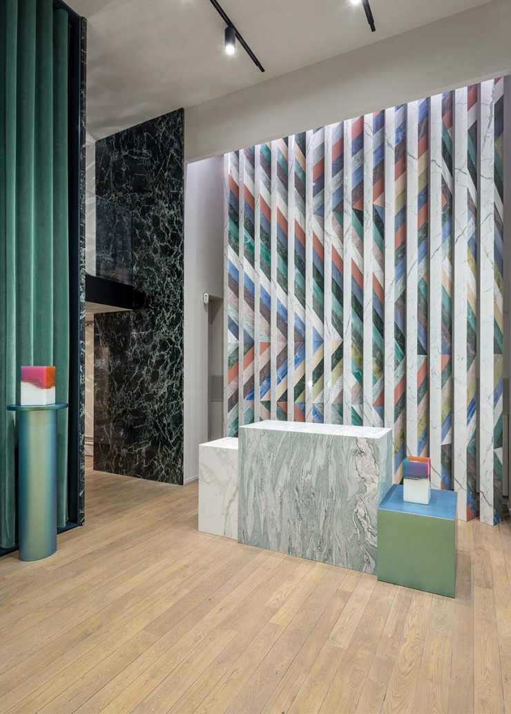 Sur fond de mur en patchwork de marbre et autres déclinaisons de pierre, dans le showroom du marbrier Budri, la collection « Agua » comprend notamment les vases Orilla, jouant avec l’onyx.