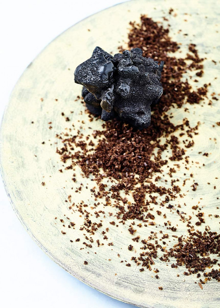 Dessert Météorite de caramel yuzu coulant – meringue torréfiée – chocolat charbon, poudre de marc de shoyu.