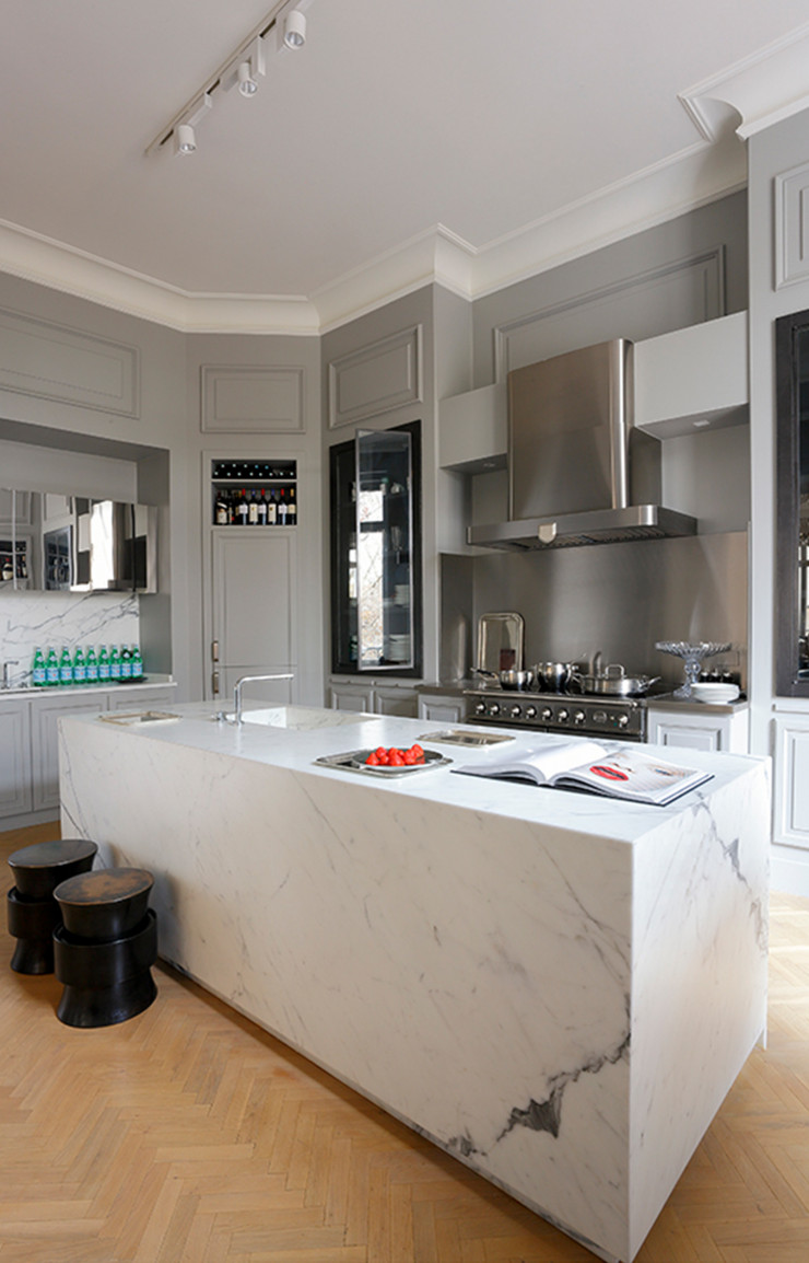 Karine Lewkowicz a transformé l’une des trois pièces de réception en enfilade de cet appartement parisien en cuisine. Tout a été réalisé sur mesure pour donner l’impression que cette dernière a toujours été là : les meubles à moulures, l’îlot en marbre de Carrare, les façades vitrées ou en polymiroir…