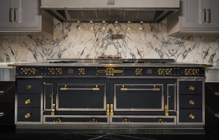 Chez La Cornue, le modèle Château Suprême possède deux étuves, une table de cuisson avec billot en noyer, une hotte habillée de cuir avec détails en métal, une plaque pour mijoter gravée d’étoiles, des plinthes Art déco… (Design Ferris Rafauli pour La Cornue).