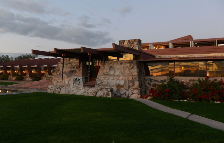 Taliesin West au crépuscule. La maison-atelier en pierre de moellons, en verre et métaux ocre, épouse en toute splendeur les rougeoiements du ciel et du paysage arizoniens.