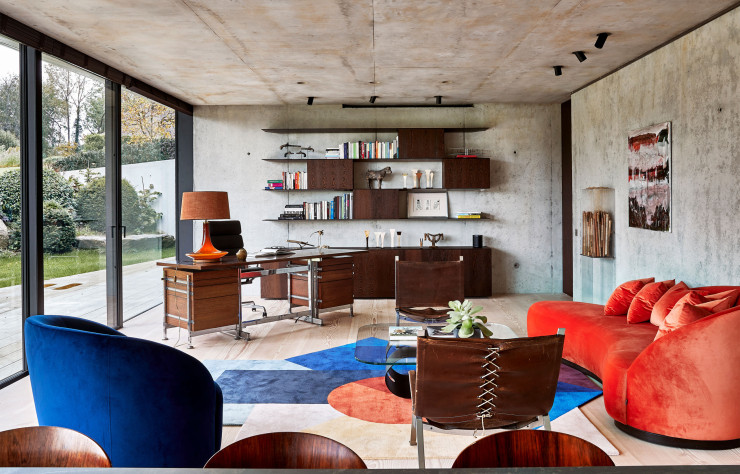 Dans le salon, bureau de Jules Wabbes (Mobilier Universel) et bibliothèque murale conçue par Bruno Erpicum. Sièges en cuir vintage. Table basse Ring de Gianluigi Landoni (Sovet Italia). Canapé et fauteuil de la collection « Euforia System », signée Edi & Paolo Ciani (Montbel). Tapis Zoe Kubb de Daria Zinovatnaya (Gan Rugs). À droite, œuvre Mémoire ludique de Mireille Desguin. Peinture de Dominique Ijak.
