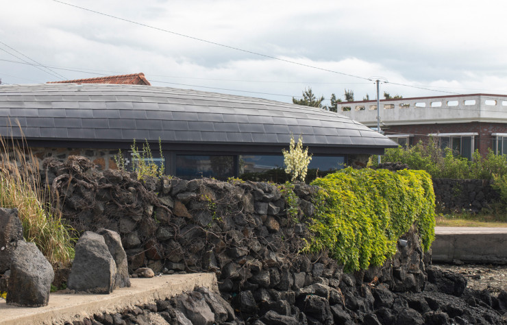 Voici la version contemporaine de la chojip, maison traditionnelle de Jeju à toit bombé. Habituellement couvert de chaume, de textile et de corde, celui-ci est ici fait de zinc. Il coiffe des murs en pierre volcanique issue d’une ancienne habitation en ruine. L’ensemble est signé Z_Lab, l’agence séoulite dirigée par l’architecte Park Jung-hyun, qui, sur toute l’île a semé de petits bâtiments aussi audacieux que respectueux.