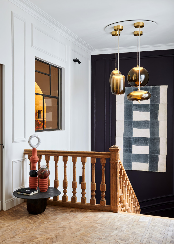 La rampe de l’escalier en chêne est d’origine. En chêne toujours, mais clair, le parquet Oscar Ono, assemblé en forme de rosace, réfléchit la lumière. Table basse de l’architecte et designer Benoit Viaene. Dessus, totems en céramique « Villa Arev » de Gabrielle Thomassian. Suspensions Knot en verre soufflé d’Ali Siahvoshi et Marco Marin (Brokis). Au mur, tableau de Jean-Pierre Pincemin (1944-2005).